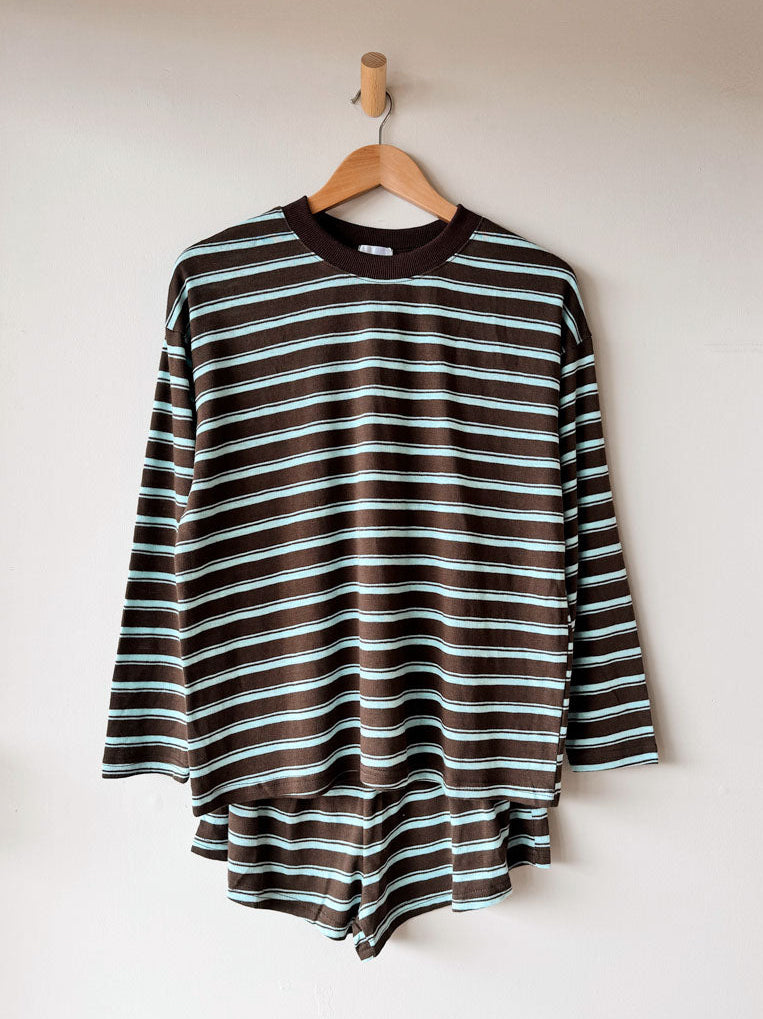 Striped long-sleeve shirt on a hanger against a white wall