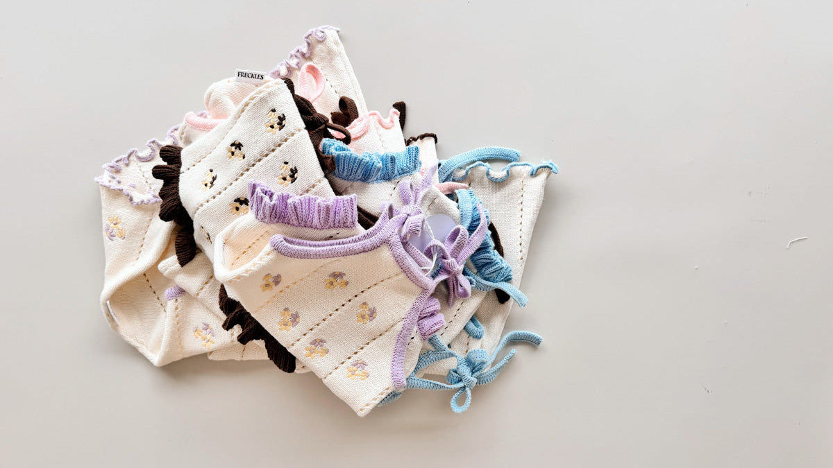 A stack of baby embroidered rompers and tie dresses