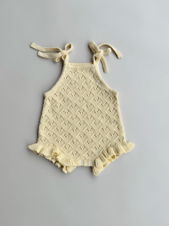 butter baby romper with lace details on a gray background